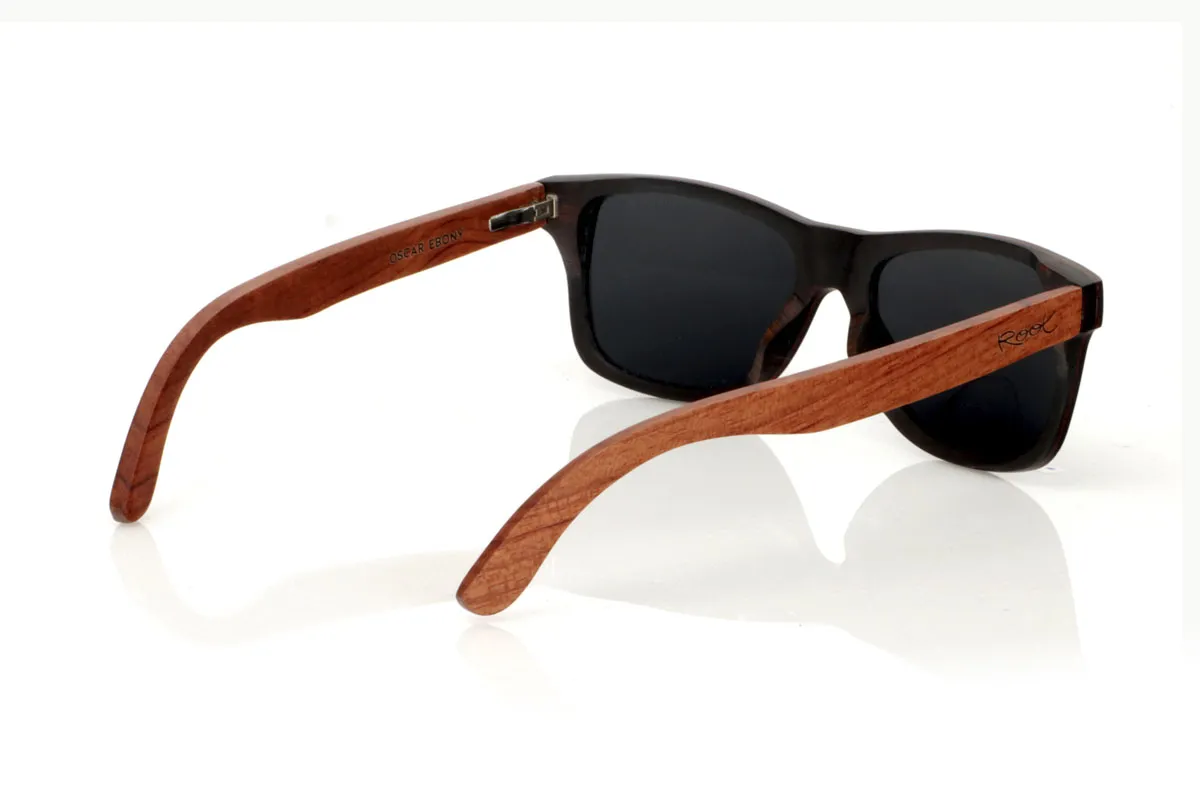 Wood eyewear of Ebony OSCAR. Gafas de sol de madera OSCAR, destaca su estilo inspirado en los clásicos, ofreciendo una silueta ancha que capta la atención. Estas gafas están meticulosamente fabricadas en capas de madera laminada, combinando ébano en el exterior y caoba en el centro, creando un efecto visual único y elegante, realzado por remaches plateados en el frontal. Las varillas de caoba prometen no solo estilo, sino también una durabilidad excepcional. Además de su diseño impecable, las OSCAR garantizan una visión clara y una protección total, asegurando que tus ojos estén protegidos con el máximo confort. Medidas: 149x45 mm. Calibre: 54. Con las OSCAR, experimentarás la perfecta unión entre moda y funcionalidad. for Wholesale & Retail | Root Sunglasses® 